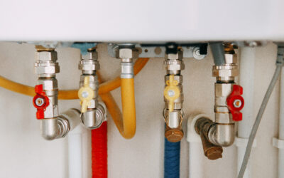 Close-up view of water heater pipes and valves in a utility room, featuring colorful connectors and tubes. Essential components for heating system maintenance and operation. Gas boiler taps.